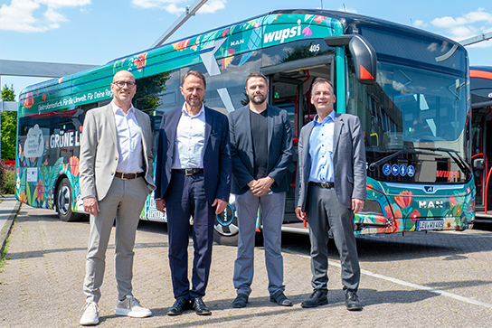 Das Bild zeigt vier Herren vor einem E-Bus der wupsi