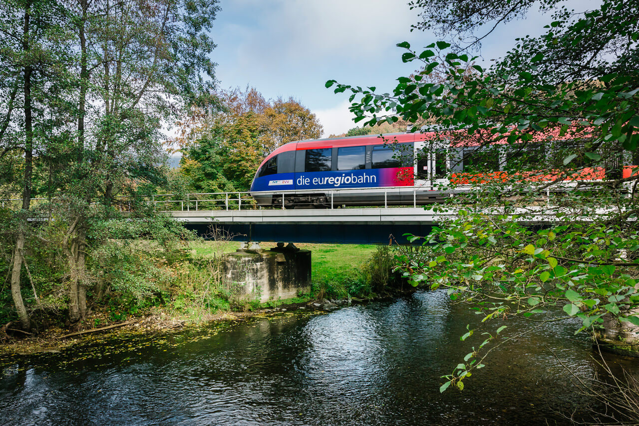 Die euregio-Bahn fährt über eine Brücke an einem sonnigen Tag