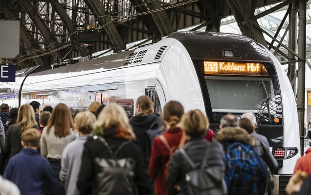 Wartende Menschen am Gleis, die in einen Zug Richtung Koblenz einsteigen